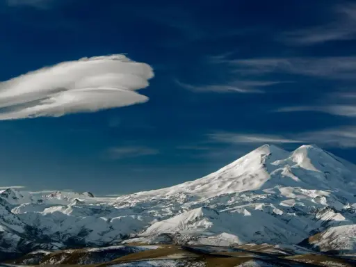 Elbrus szczyt w chmurach lenticularnych. Majestatyczne, ośnieżone góry pod błękitnym niebem.