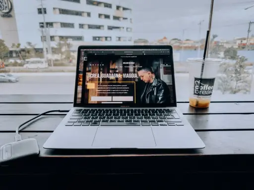 Un laptop aperto su un sito web che spiega cosa fa un content creator, con una bevanda accanto.