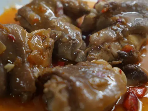 Manitas de cerdo en salsa, un plato de comida típica de Valladolid, con trozos de pimiento y cebolla.