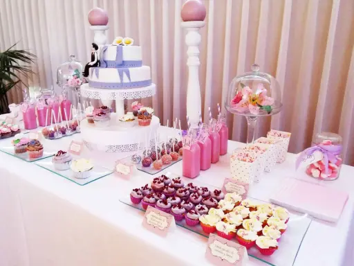 Mesa dulce para 50 cumpleaños con pastel de dos pisos, cupcakes, cake pops, bebidas rosas y palomitas.