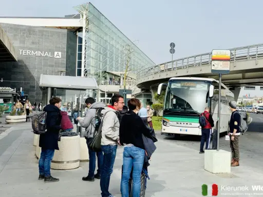 Ludzie czekają na autobus przed Terminalem A na lotnisku w Katanii.