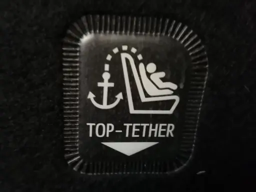 Symbol mocowania fotelika ISOFIX z kotwicą i dzieckiem. To jest oznaczenie TOP TETHER.