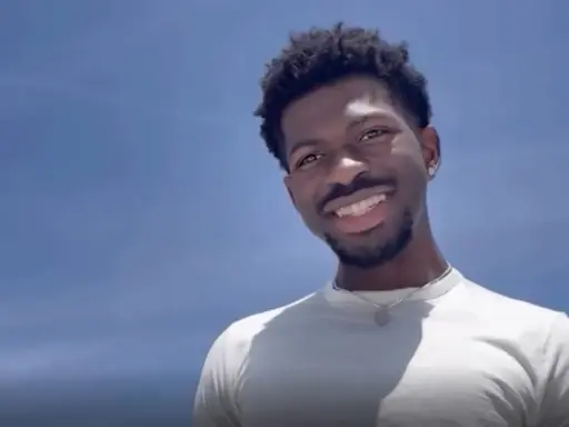 Lil Nas X, uśmiechnięty na tle błękitnego nieba. Czy Lil Nas X jest gejem? To pytanie często pojawia się w dyskusjach o jego życiu.