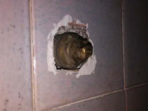 Parte interna di un rubinetto in ottone, incassato nel muro piastrellato. La chiusura del rubinetto acqua senso è necessaria per evitare perdite.