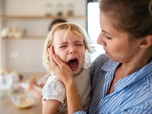 Mama próbuje uspokoić dziecko, które przeżywa histerię. Płacz malucha jest bardzo intensywny.