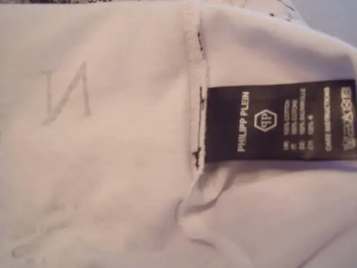 Etikett mit "Philipp Plein" und dem PP-Logo. Ein undeutliches "N" ist auf dem Stoff zu sehen. So erkennt man ein Philipp Plein Fake.