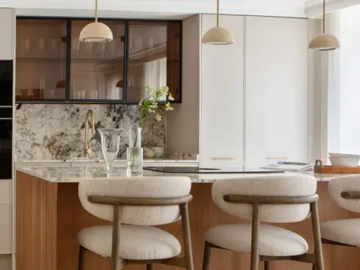 Cocina moderna con isla central, taburetes y electrodomésticos integrados. Un diseño atemporal que combina funcionalidad y elegancia.