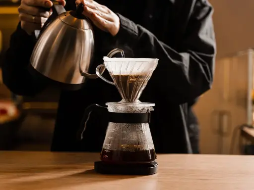 Person gießt heißes Wasser über Kaffeepulver in einem Filter. Die richtige filterkaffee temperatur ist entscheidend für den Geschmack.