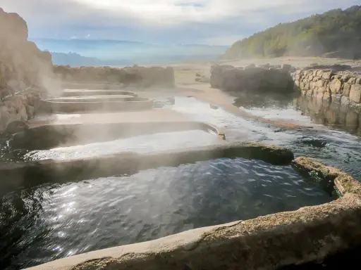 Tierras de vapor y agua en las termas naturales Galicia. Un paisaje sereno con piscinas escalonadas y muros de piedra.