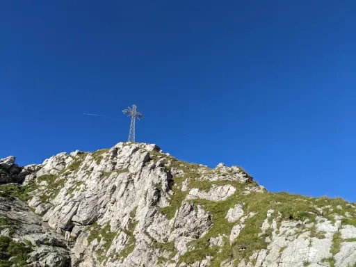 Kamienista trasa na Giewont prowadzi pod górę, gdzie widać krzyż na szczycie.