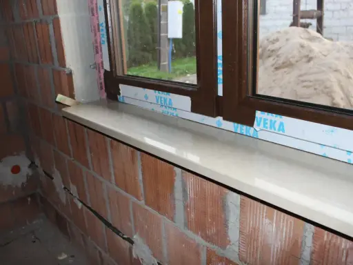 Montaż parapetów wewnętrznych najlepiej wykonać po otynkowaniu ścian, ale przed położeniem podłóg. Widoczny parapet czeka na wykończenie.
