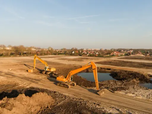 Excavadoras trabajan en un sitio de remediación de suelos, moviendo tierra y agua para restaurar el terreno.