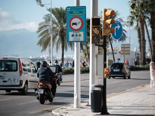Señal de zona de bajas emisiones en Vigo. Coches y motos circulan bajo palmeras.