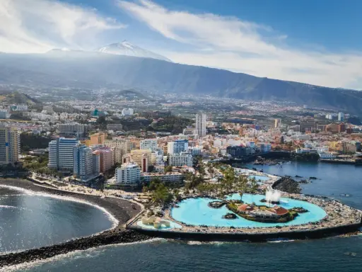 Puerto de la Cruz atrakcje: Lago Martianez, baseny z wodą morską, plaża, miasto i wulkan Teide w tle.