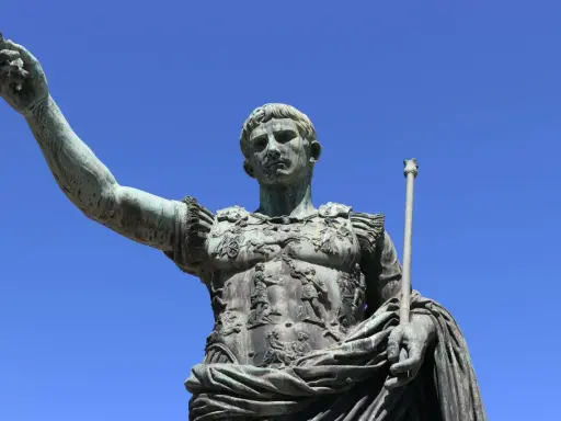 Bronzestatue eines römischen Kaisers, der mit erhobener Hand und Zepter auf den Betrachter blickt. Sie symbolisiert, wie wurde Rom regiert.