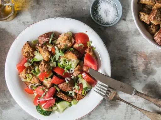 Ein erfrischender toskanischer Brotsalat mit Tomaten, Gurken und knusprigen Brotwürfeln, garniert mit frischen Kräutern.