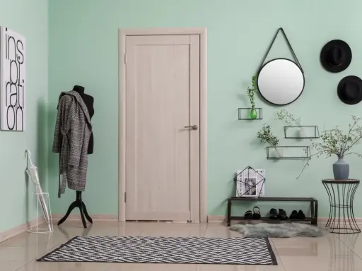 Miętowy kolor ścian świetnie komponuje się z czernią i drewnem. W przedpokoju widać płaszcz na manekinie, czarne kapelusze i lustro.