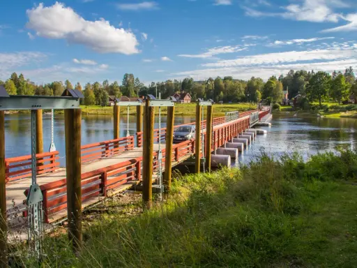 En bil kör över flottbron i Gagnef en solig dag.