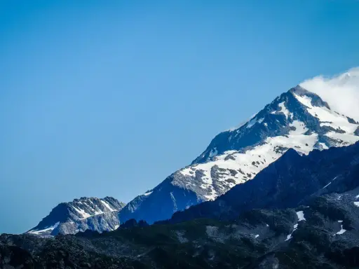 Majestatyczne szczyty Alp, pokryte śniegiem, z błękitnym niebem. Widok na trasę Tour du Mont Blanc.