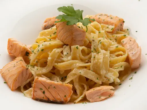 Deliciosa pasta con trozos de salmón rosado, cubierta con una cremosa salsa y espolvoreada con perejil fresco.