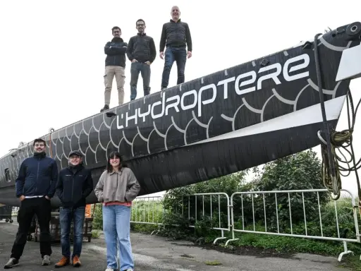L'équipe pose fièrement devant l'hydroptère 2.0, un navire futuriste prêt à fendre les flots.