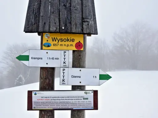 Szlak w Magurskim Parku Narodowym. Znak wskazuje Wysokie (657 m n.p.m.), najwyższy szczyt, oraz kierunki do Krempnej i Ożennej.