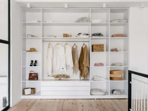 Idéal pour aménager un placard : étagères blanches remplies de vêtements, accessoires et boîtes.