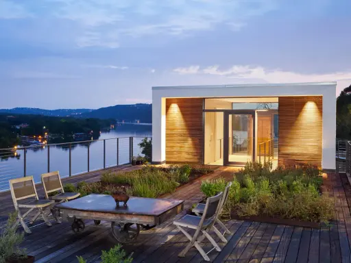 Moderner dachgarten auf einem Flachdach mit Blick auf einen See. Holzdeck, Sitzgelegenheiten und üppige Bepflanzung laden zum Entspannen ein.