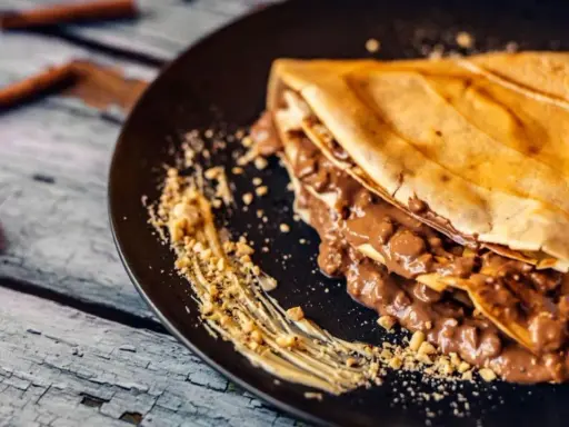 Crepe doblada con relleno cremoso de chocolate y trocitos de frutos secos. Una deliciosa receta crepes para disfrutar.
