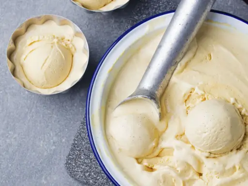 Krämig vaniljglass, perfekt för ett enkelt gelato recept. En skopa glass i en form och en stor skål med glass och skopa.