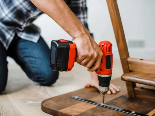 Un homme assemble un meuble en bois avec une perceuse. Un projet de bricolage maison réussi.