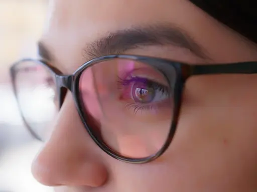 Zbliżenie oka w okularach, odbicie światła sugeruje, że optometrysta źle dobrane szkła.