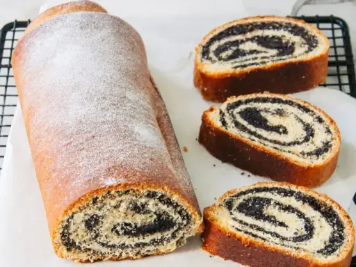 Stary przepis babci na makowiec. Puszysty, pachnący makowiec z cukrem pudrem, pokrojony na plastry, odsłaniający bogate nadzienie makowe.