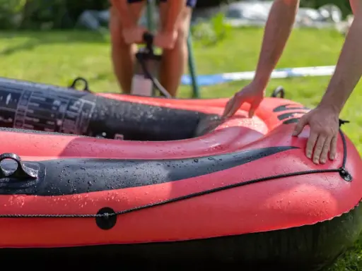 Hände bereiten das Schlauchboot vor, während im Hintergrund jemand pumpt.