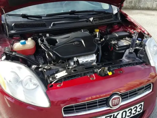 Czerwony Fiat Bravo 1.4 T-Jet z otwartą maską, widoczny silnik i reflektor.