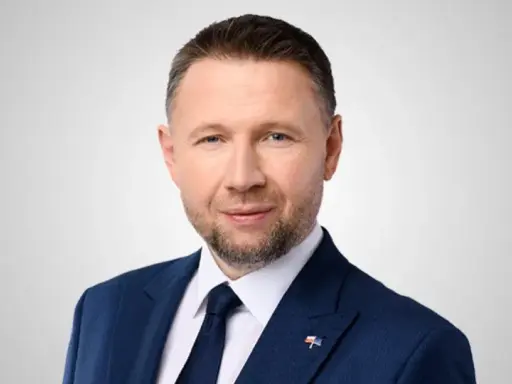 Mężczyzna w granatowym garniturze, z krótkimi włosami i zarostem, to minister spraw wewnętrznych.