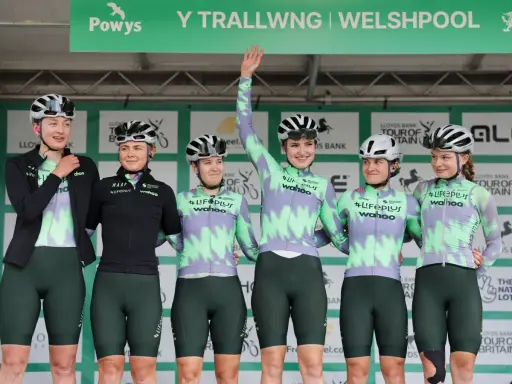 Sechs Radfahrerinnen des Lifeplus Teams stehen auf einem Podium, einige winken.