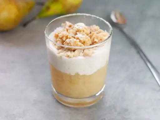 Ein Glas mit Birnenkompott, Sahne und Streuseln. Perfekt, wenn man etwas Süßes sucht, das gut zu Birnenkompott passt.
