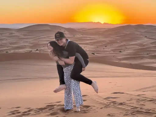 Jóvenes disfrutando de un atardecer en las dunas de Marruecos con niños.