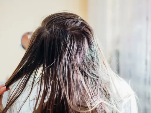 Nasse Haare, die nur mit Wasser gewaschen wurden, werden von einer Hand durchkämmt.
