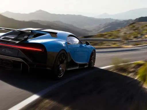 Blauer Bugatti Chiron Pur Sport rast auf einer kurvigen Bergstraße.