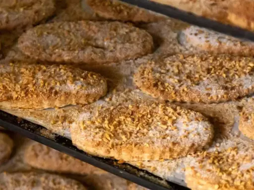 Varias cocas de llardons recién horneadas, cubiertas de azúcar y trocitos de frutos secos, listas para disfrutar.