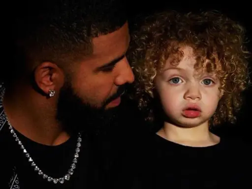 Drake i jego syn, Adonis, w czarnych ubraniach. Chłopiec ma kręcone, jasne włosy i niebieskie oczy.