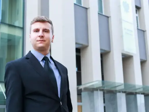 Mężczyzna w garniturze przed nowoczesnym budynkiem.