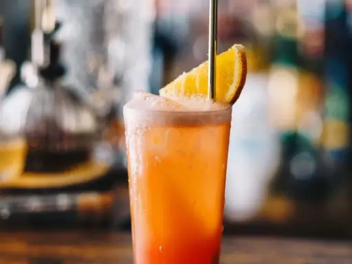 Orzeźwiający drink Garibaldi z plasterkiem pomarańczy i złotą słomką, idealny na letnie popołudnie.