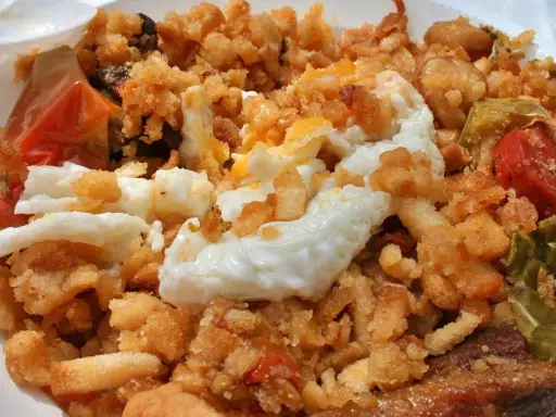 Plato de migas con huevo frito, pimientos y tomate, un delicioso ejemplo de comida típica de Jaén.