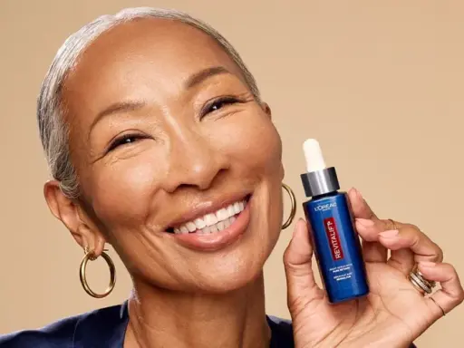 Mujer sonriente muestra un sérum Revitalift con retinol, ideal para rejuvenecer la piel y combatir arrugas.