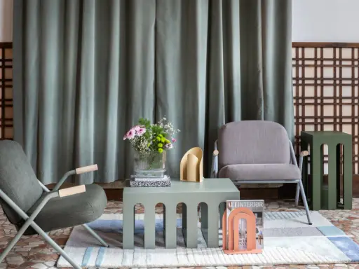 Un salotto con sedie grigie, tavolini verde salvia e un tocco di rosa pesca. Idee per colori da abbinare con il grigio chiaro.