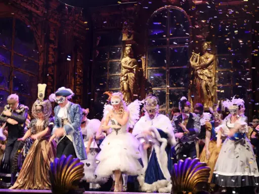 Scena z "Upiora w Operze" – barwny bal maskowy z konfetti.