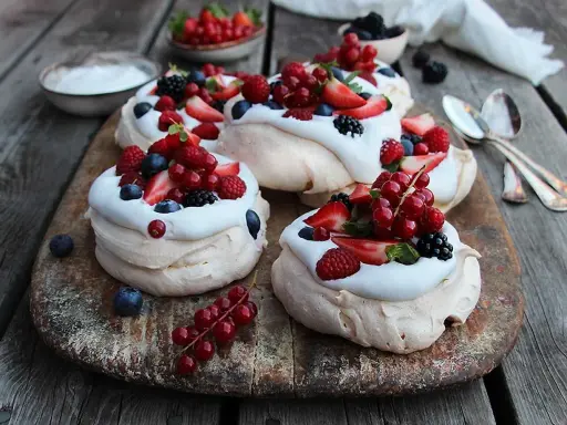 Små pavlovakakor med vispgrädde och färska bär som jordgubbar, hallon, blåbär och vinbär. En härlig sommardessert!